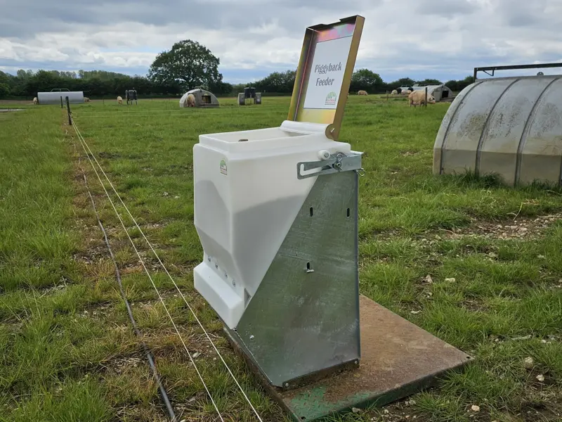 Piggyback feeder on a metal farrow feeder with lid open